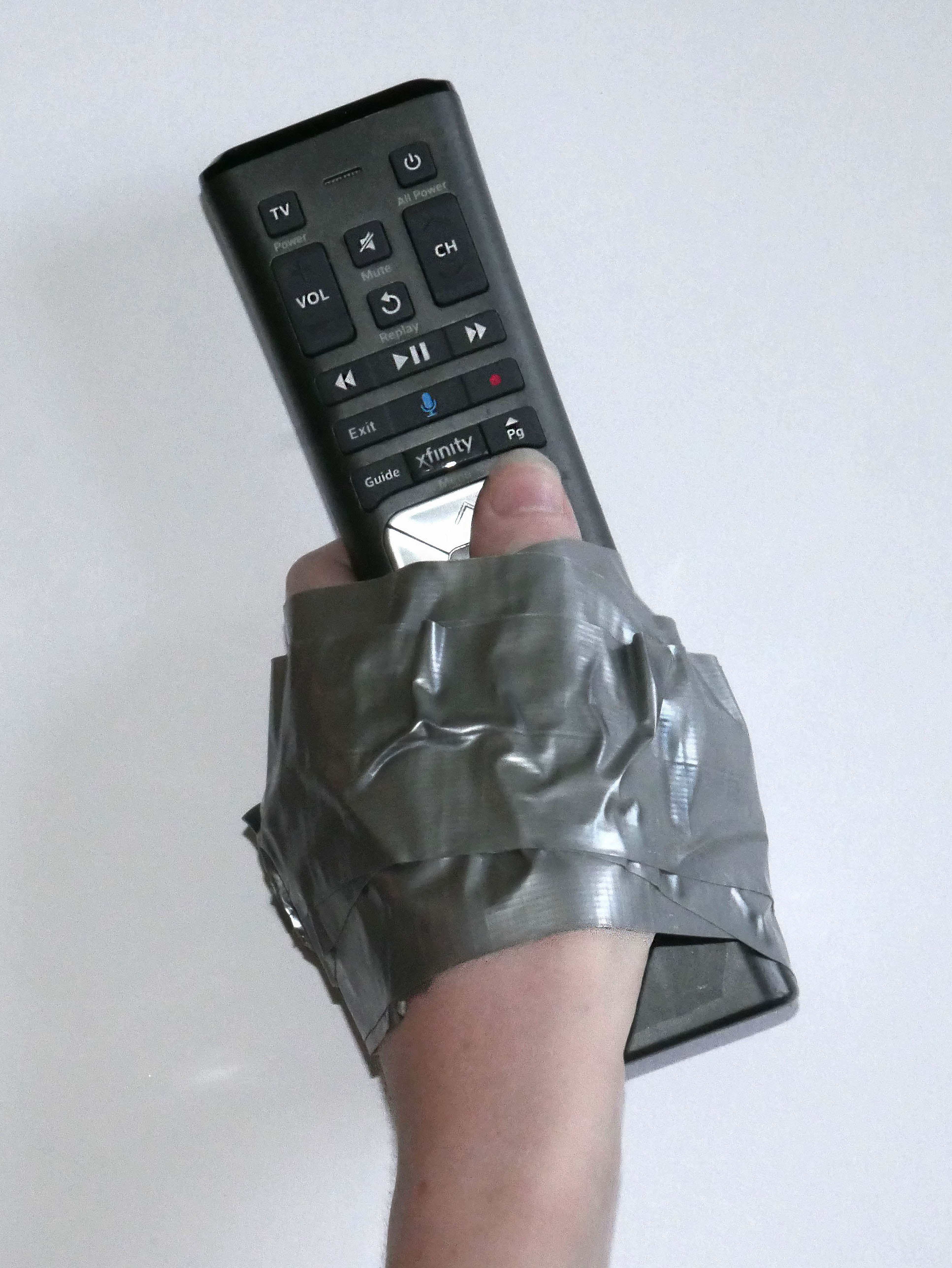 Photograph of a human hand duct taped to a television remote control.
