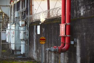 A sign reading "Petroleum Pipeline" sits beneath a barbed wire fence next to two bright red spigots.