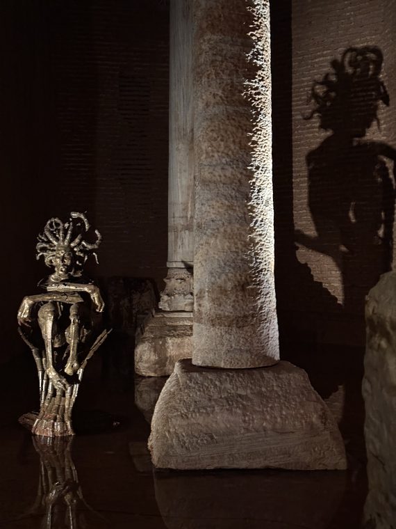A sculpture sits next to an ancient pillar, displaying the art exhibit spoken of in the article.