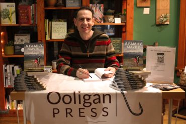 Photo of Lane Igoudin at a table with his books displayed